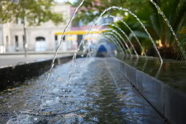 A long trough of a water feature, with foundtains of water arcing across it