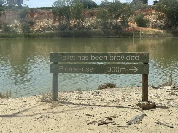 A sign on the riverbank saying 'Toilet has been provided, please use', with an arrow