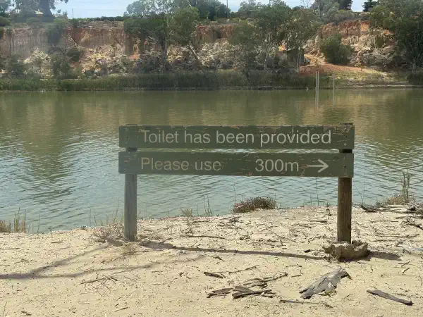 A sign on the riverbank saying 'Toilet has been provided, please use', with an arrow