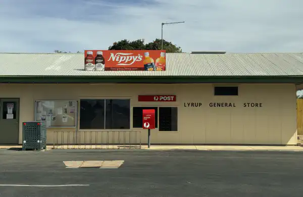 a country store and post office, with an advertisement for 'Nippys' drinks on it