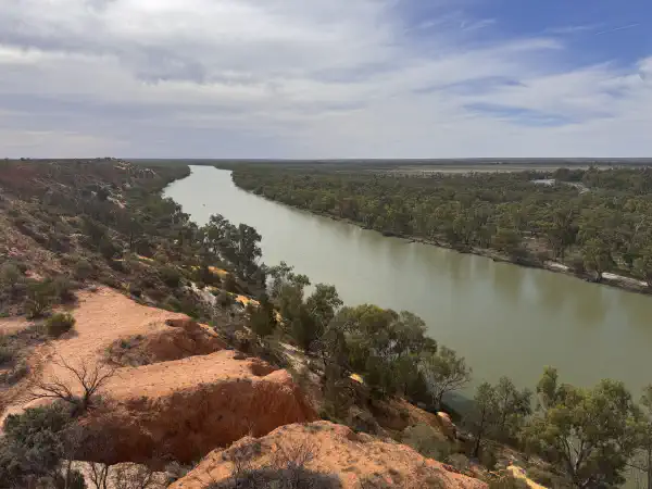 A view of the river from a high cliff, it comes from the far distance and bends away past the viewer to the right