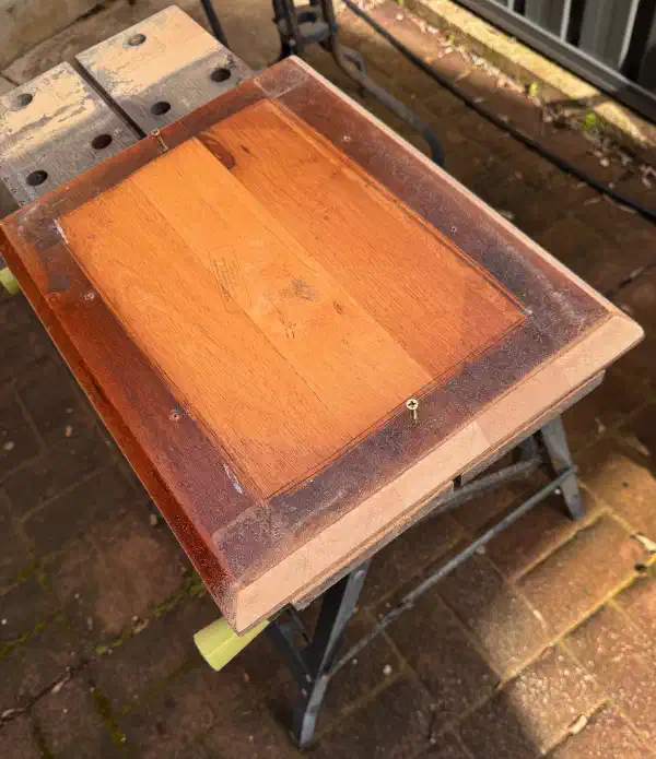 Underside of a tabletop, partially sanded back to raw wood