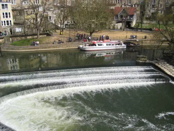 A river, with tiers of curved short waterfalls, a boat is on the far side