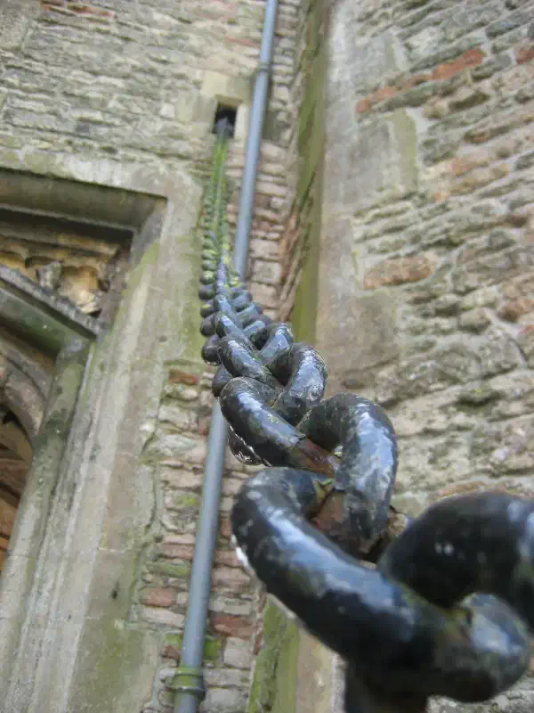 A close-up of a thick chain, leading upward to a wall